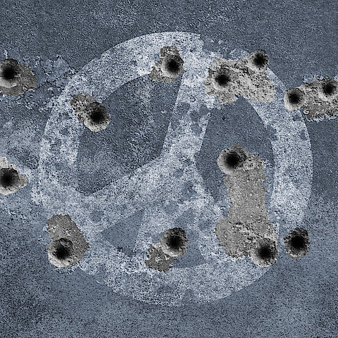 Peace symbol on a wall with bullet holes